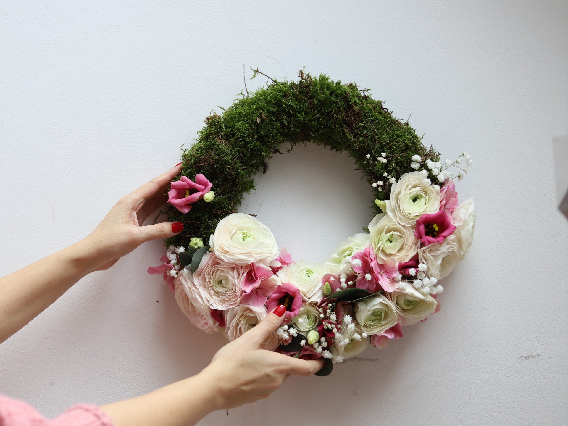 Pavasarinis vainikas su rožiniais ir baltais vėdrynais išsilaiko ilgiau dėl floristinės kempinės pagrindo.